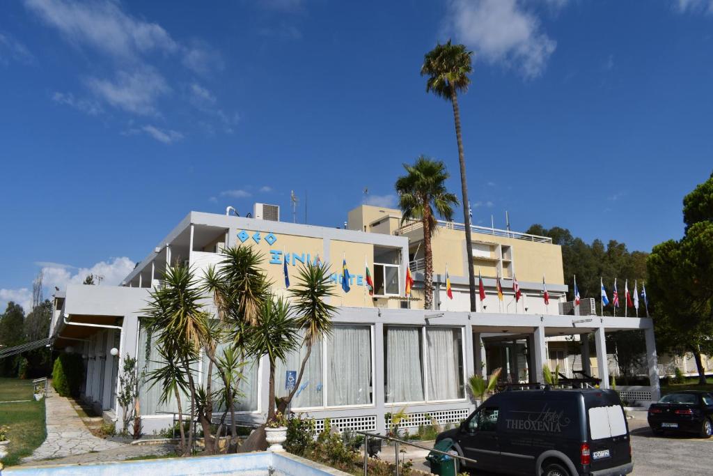 迈索隆吉翁Hotel Theoxenia的一座白色的建筑,前面有棕榈树