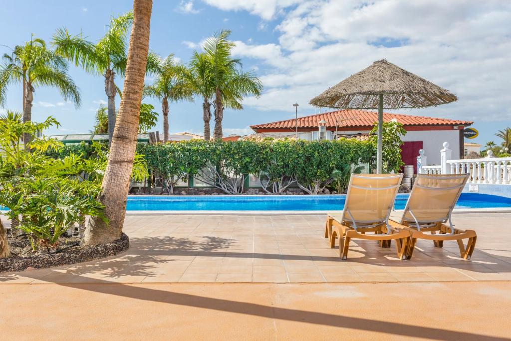 圣米格尔德阿沃纳钻石度假酒店皇家特内里费岛乡村俱乐部的游泳池旁的两把椅子和一把遮阳伞
