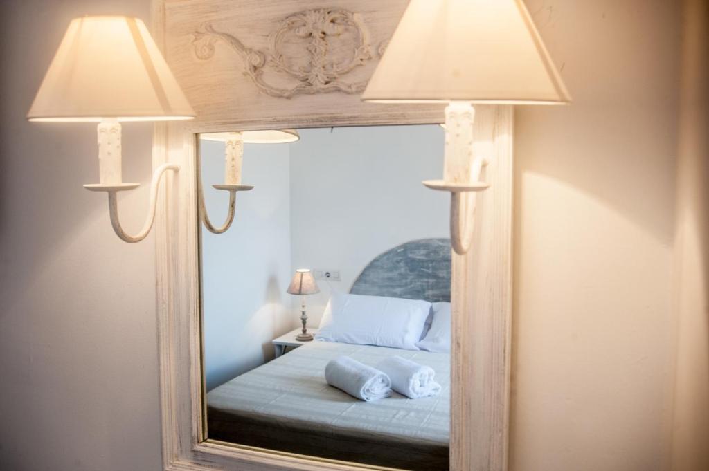 圣费兰-德瑟斯罗Hostal Bon Sol的镜子,有两盏灯和一张位于房间的床