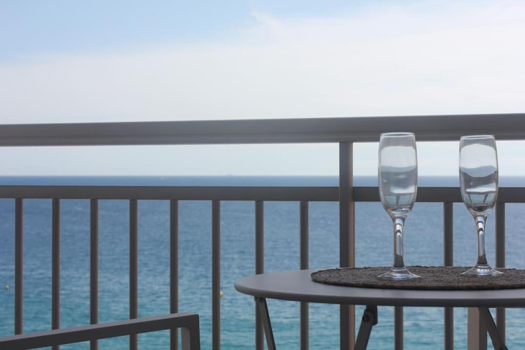 普拉加德阿罗Apartamento primera línea de mar的阳台上的桌子上放着两杯酒