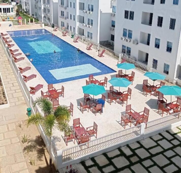 CoveñitasHermoso apartamento en Coveñas con piscina的享有带椅子和遮阳伞的游泳池的上方景色