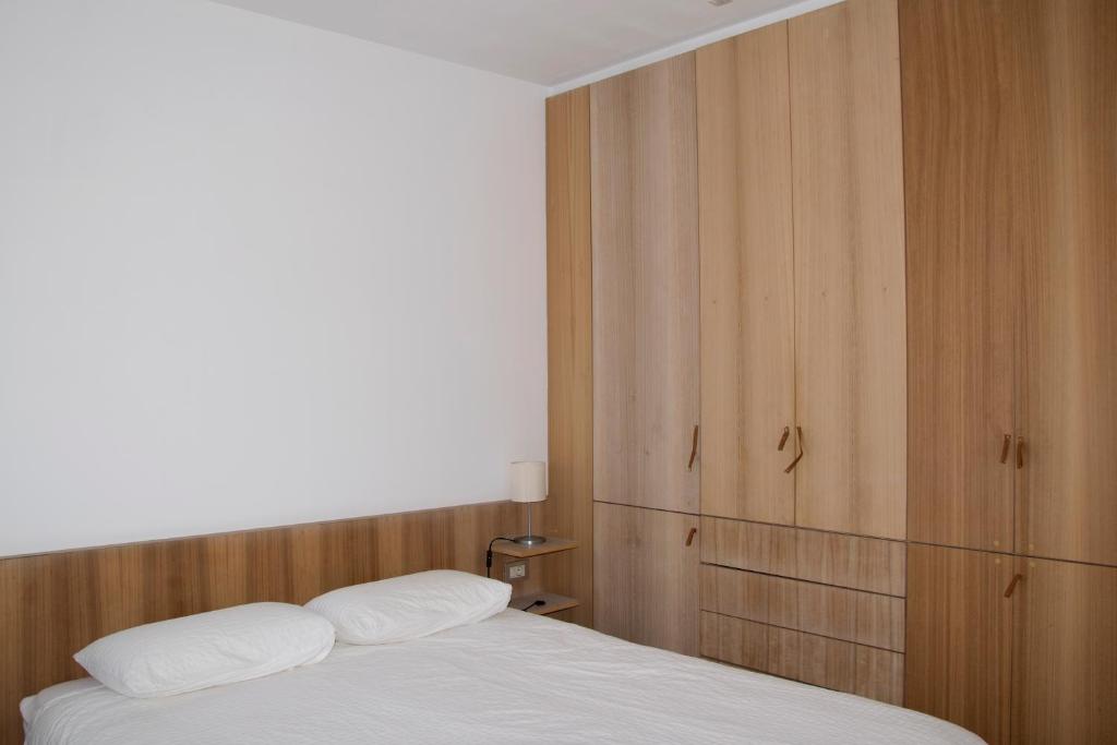 艾利亚德亚罗萨Apartamento de Mar y Playa en Illa de Arousa的卧室配有白色的床和木制橱柜。