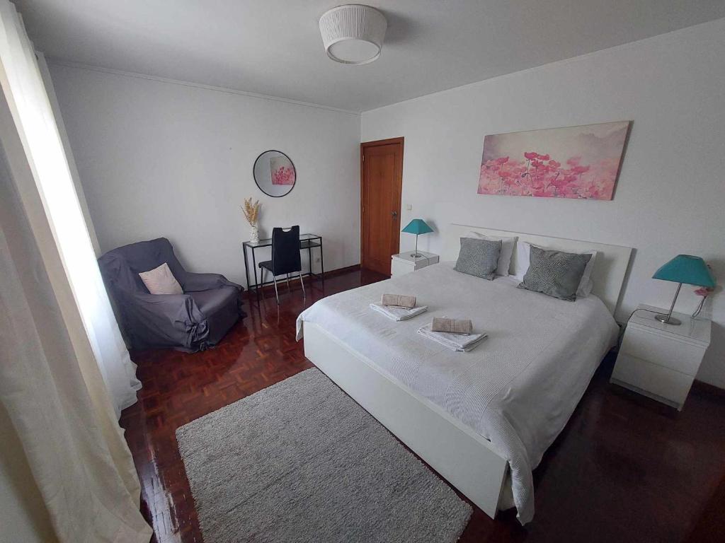 波尔图Vale Formoso Apartment的卧室配有一张白色大床和一把椅子
