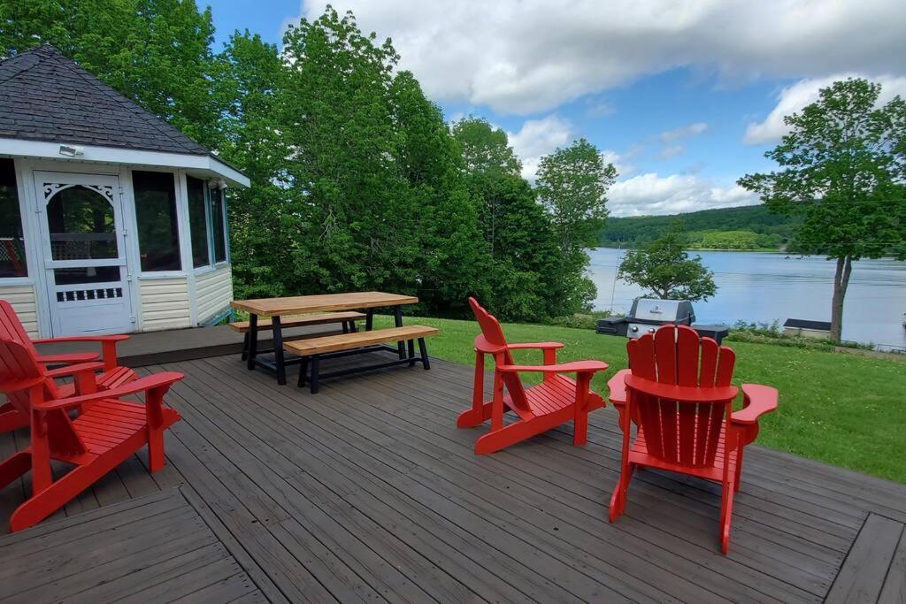 安蒂戈尼什Lochaber Lakeview Cottage的木制甲板配有红色椅子和野餐桌