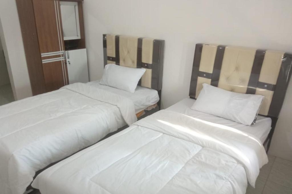ParitOYO 93100 Harapan Homestay Syariah的配有2张床的带白色床单和枕头的客房
