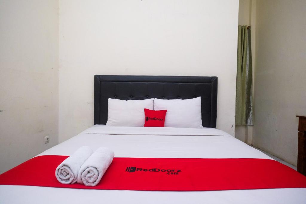 科贾扬RedDoorz Syariah at Griya Hanum Condoongcatur的卧室配有红色和白色的床和2条毛巾