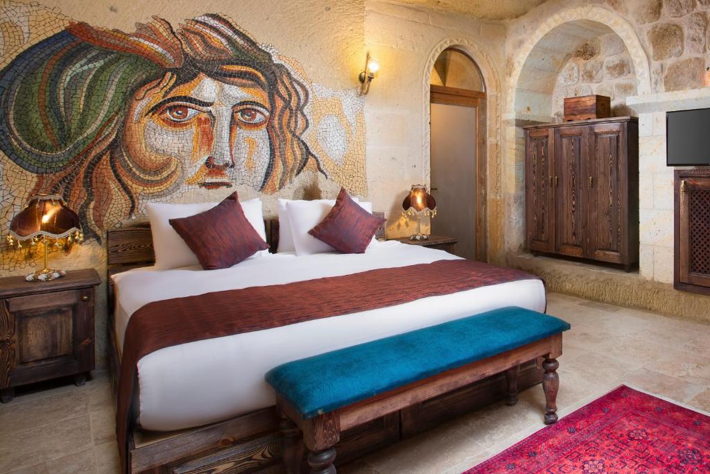 奥塔希萨尔Cappadocia Pema Cave Hotel的卧室配有一张大床,墙上挂有绘画作品