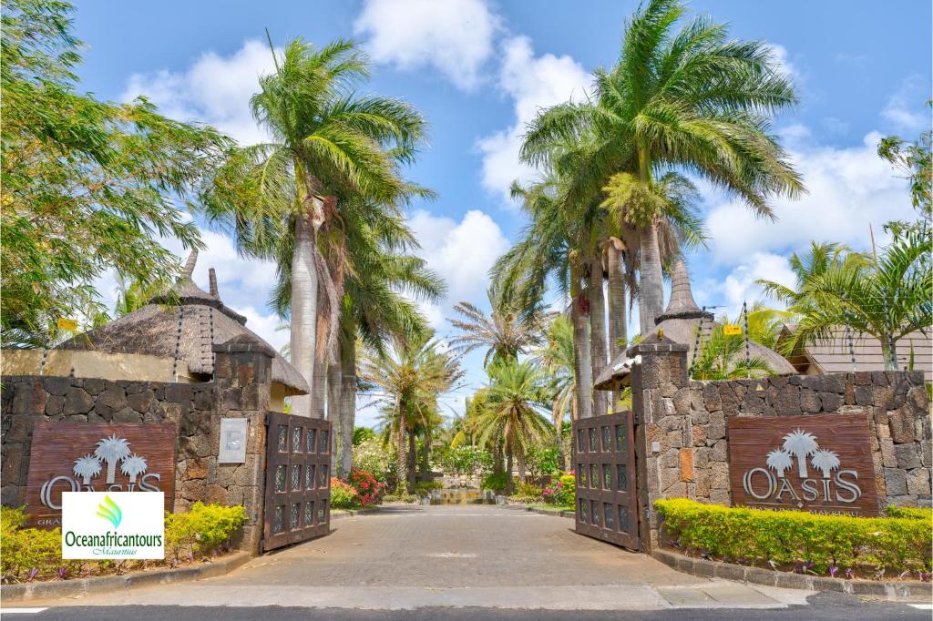 格兰贝伊Oasis 1 Villa Tropicale的棕榈树度假村入口处的大门