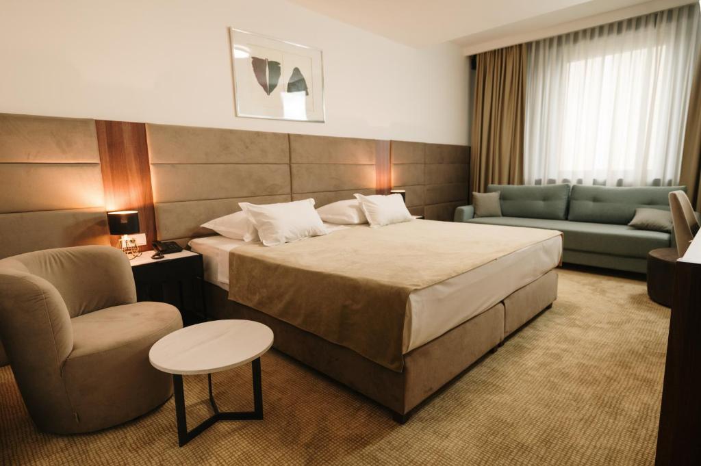 贝尔格莱德Hotel Slavija Lux的酒店客房配有一张床、一把椅子和一张沙发