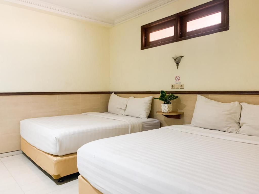 日惹Musafira Hotel Syariah Malioboro Yogyakarta Mitra RedDoorz的配有2张床的白色墙壁和窗户客房