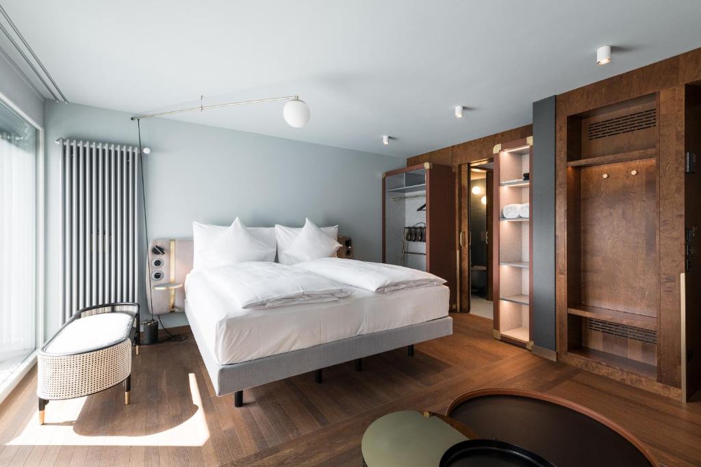 图恩Hotel Aare Thun的卧室配有一张白色大床和一把椅子
