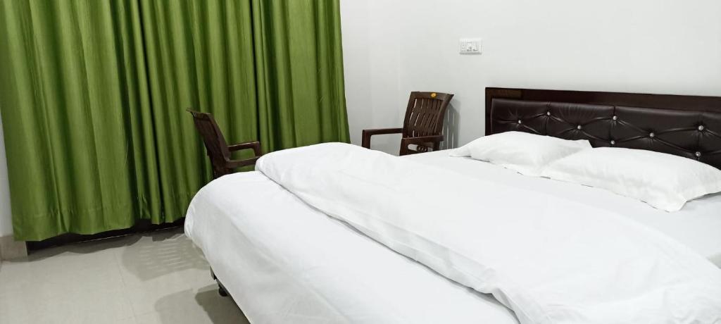 达兰萨拉RADHA BNB ( HOMESTAY )的一间卧室配有两张白色的床和绿色窗帘