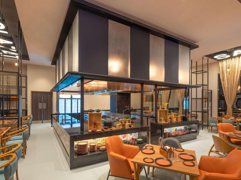 塞恩ibis Thane - An Accor Brand的一间餐厅,房间内设有橙色椅子和桌子