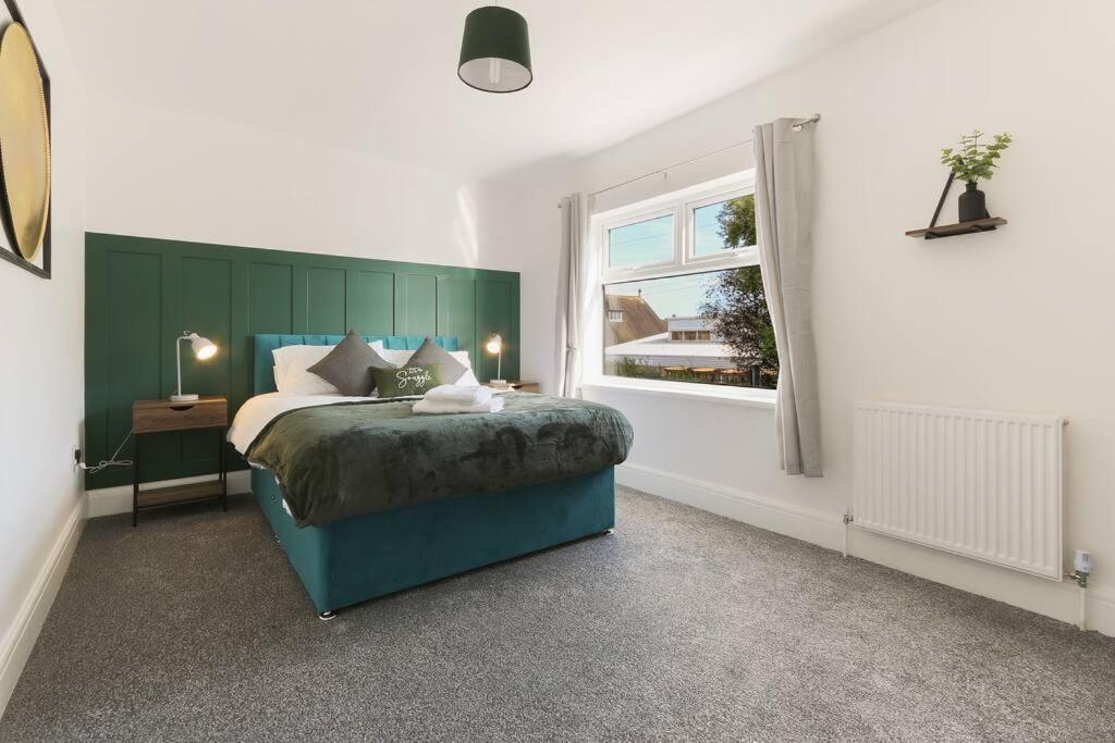 Great CoatesModern home near Alexandra Dock的一间卧室配有一张带绿色床头板的床和窗户