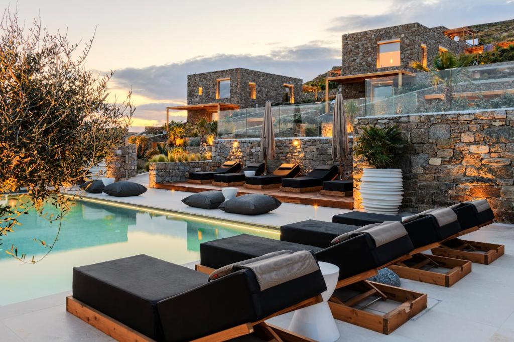 米克诺斯城Nasta Suites & Villas Intentional Living Mykonos的一个带躺椅的户外庭院和一个游泳池