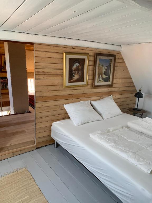 马斯塔尔Timberframe house near Marstal Harbour的卧室配有白色的床和墙上的两张照片