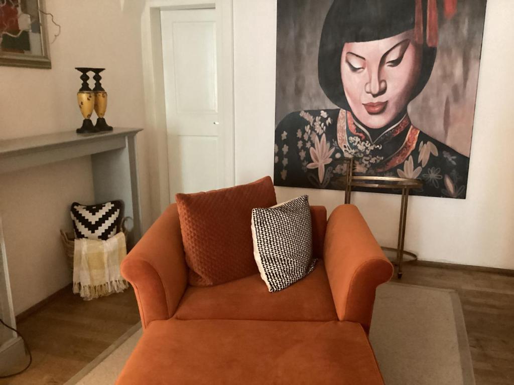 布拉格Nana Macs的客厅里一张橙色的沙发,上面有绘画作品
