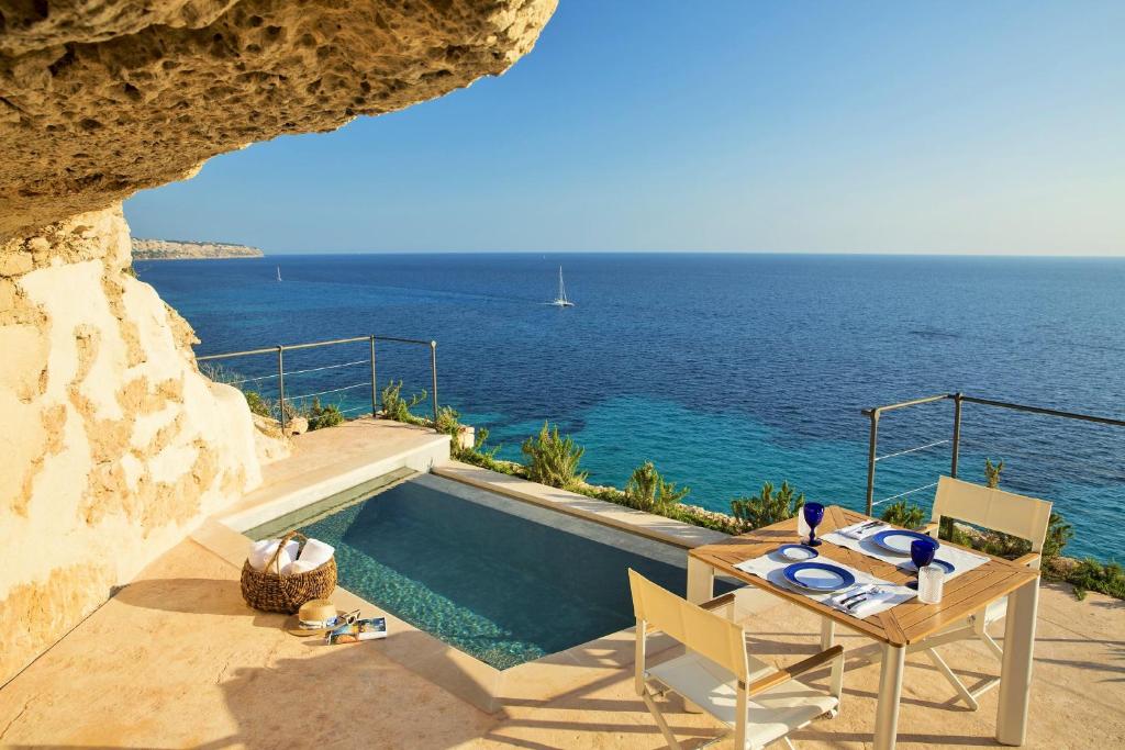卡拉布拉瓦Cap Rocat, a Small Luxury Hotel of the World的一个带桌椅的游泳池以及大海