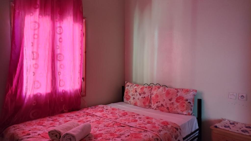 廷吉尔Myhouse Todgha的一间卧室配有粉红色的窗帘和一张带两个枕头的床