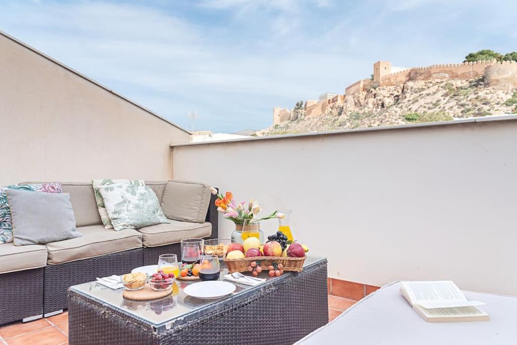 阿尔么丽亚Casa flamenca a los pies de la Alcazaba的阳台配有带水果的桌子和沙发。