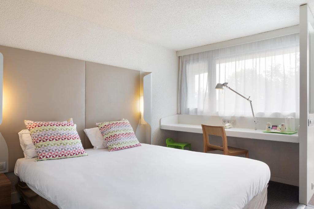 马恩河畔博纳伊克莱特伊康铂酒店 - 博纳伊苏尔马恩的卧室设有一张白色大床和一扇窗户。