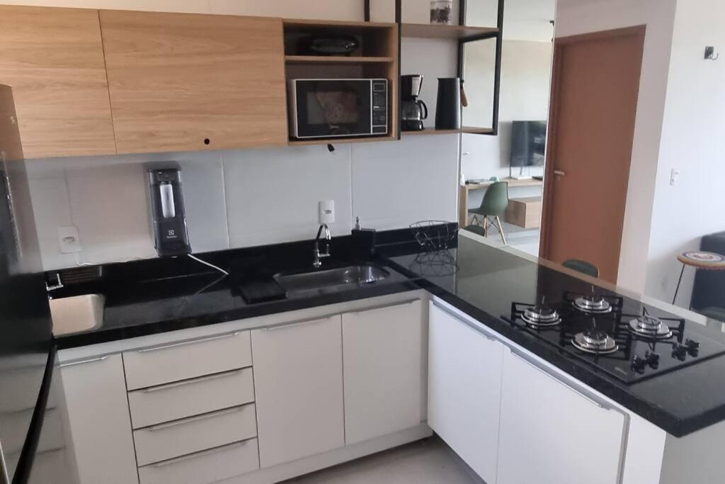 康德Cobertura Vista Mar Carapibus - Cariri Praia - Apartamento completo com 02 quartos的厨房配有白色橱柜和黑色台面