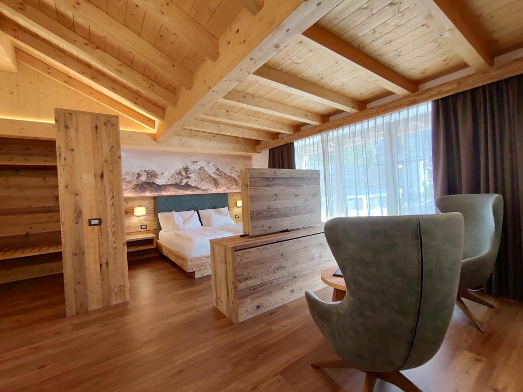 泰塞罗DOLOMITES B&B - Suites, Apartments and SPA的一间卧室配有一张床、一张桌子和一把椅子