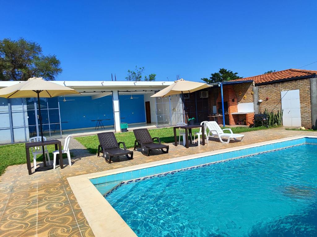 San Lorenzo de la FronteraALOJAMIENTO ASPEN HOME的房屋旁的游泳池配有椅子和遮阳伞