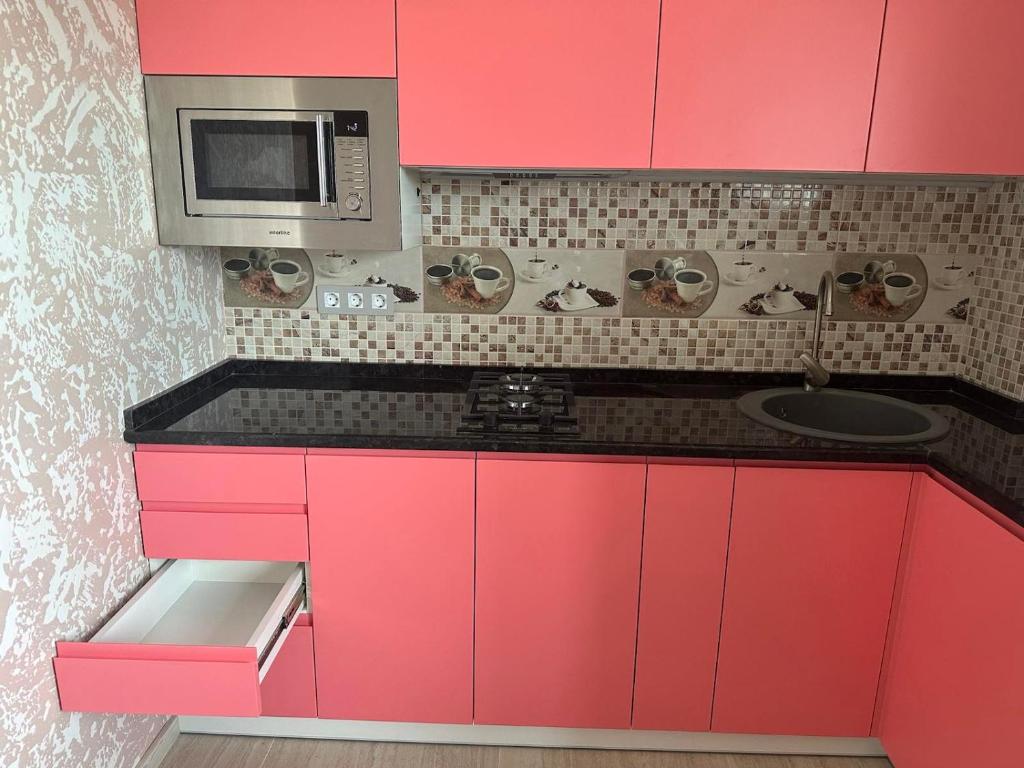 哈尔科夫Днестровский的厨房配有粉红色橱柜和微波炉