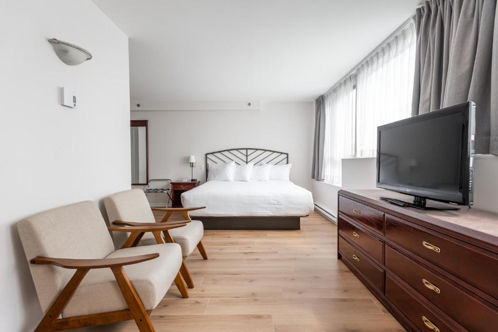 蒙特利尔拉贝尔套房酒店的一间卧室配有一张床和一台平面电视