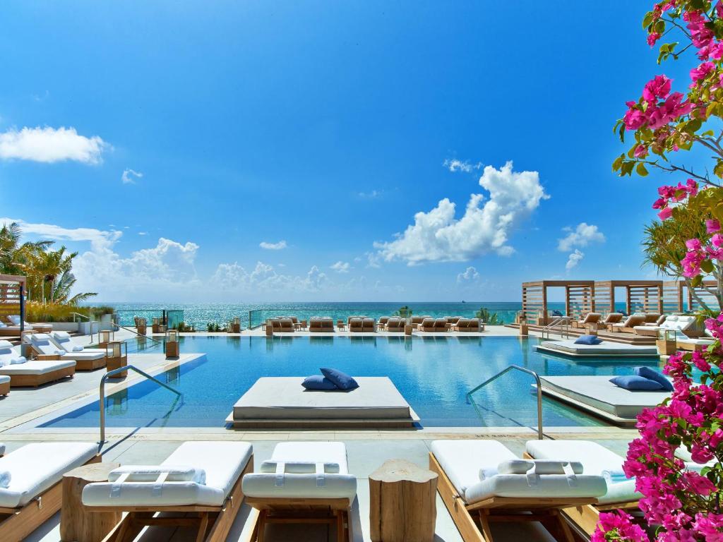 迈阿密海滩南海滩1号酒店的一个带躺椅的游泳池,背景是大海