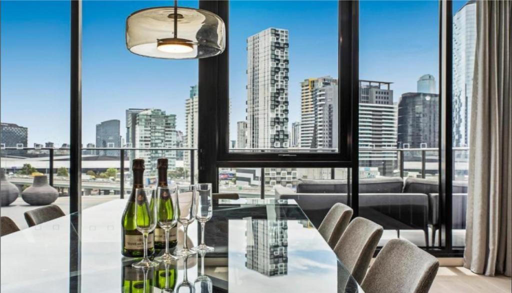 墨尔本Luxury Penthouse with Astonishing Bay and City Views的用餐室配有玻璃桌和葡萄酒瓶