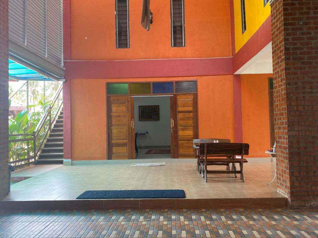 Kepala BatasLaman Norras Homestay的配有橙色墙壁、桌子和椅子的房间