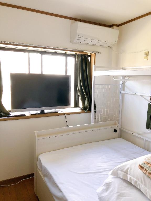 大阪HOSTEL198 Private Room of Second floorーVacation STAY68024v的一间卧室设有一张床和一个带平面电视的窗户。