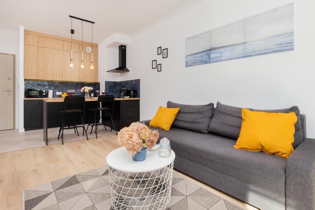 格但斯克Modern Apartment with Balcony by Renters的客厅以及带灰色沙发和黄色枕头的厨房。