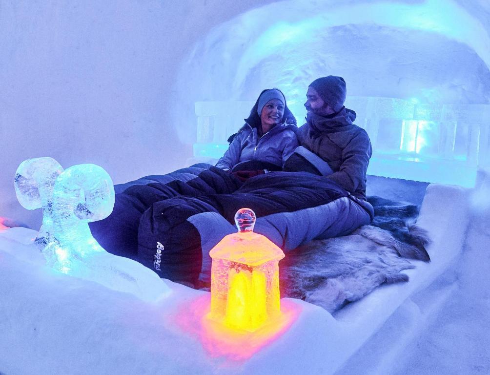 哈山Hunderfossen Snow Hotel的两人坐在冰屋里,拿着消防栓