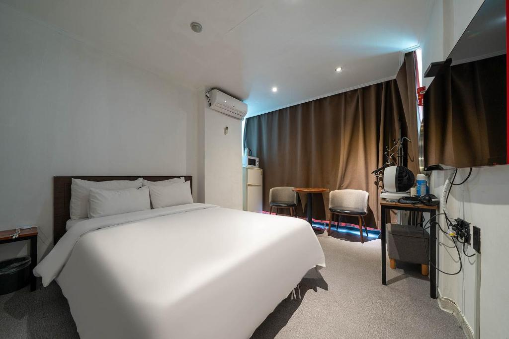 平泽市Pacific7 Hotel的卧室配有一张白色的大床和一张桌子