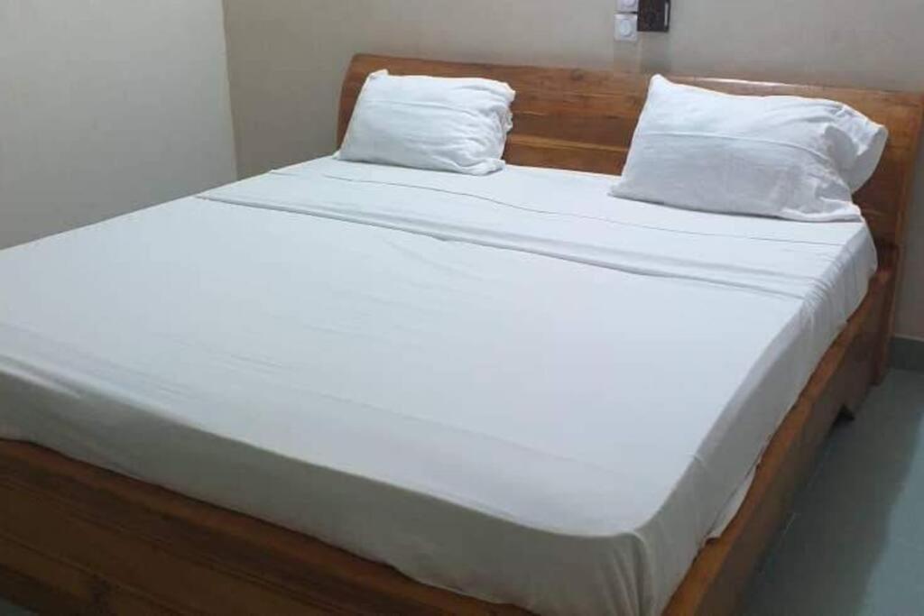 OuidahOuidah Lodge的一张带白色床单的床和两个枕头