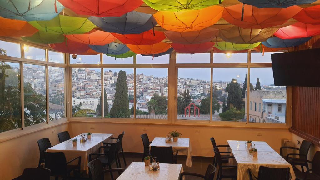 拿撒勒罗萨娜旅馆的餐厅设有挂在天花板上的桌子和遮阳伞