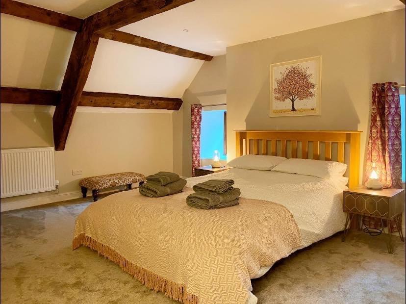塔尔加斯The Cottage at Sychnant Farm的一间卧室配有一张大床,上面有两条绿色毛巾