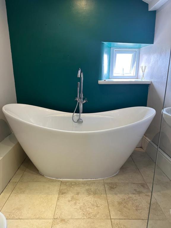 ConisbroughSugar Plum Cottage的浴室设有白色浴缸,拥有绿色的墙壁