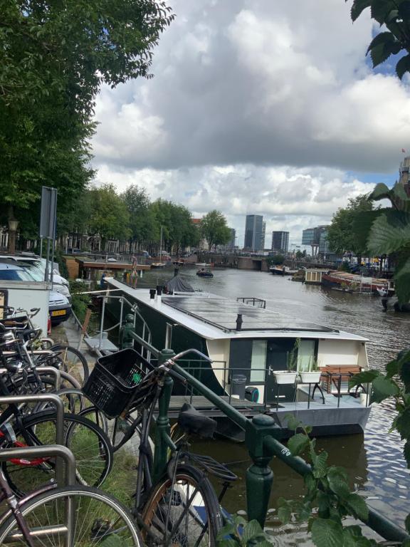 阿姆斯特丹Boat no Breakfast的一条河上的小船,旁边停有自行车