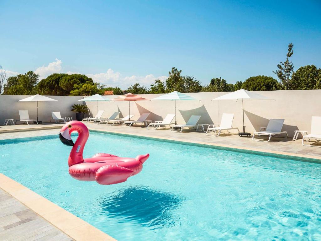 莫吉奥Ibis Styles Montpellier Aéroport Parc Des Expos的游泳池里的粉红色天鹅