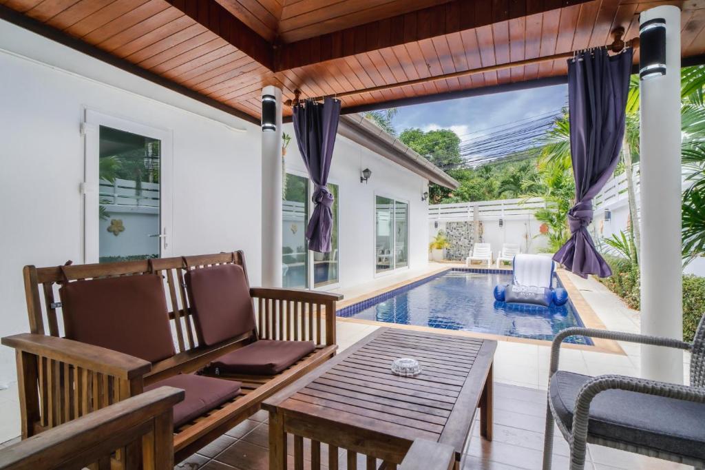 拉威海滩Jasmine Pool Villa in Nai Harn的一个带桌椅的庭院和一个游泳池