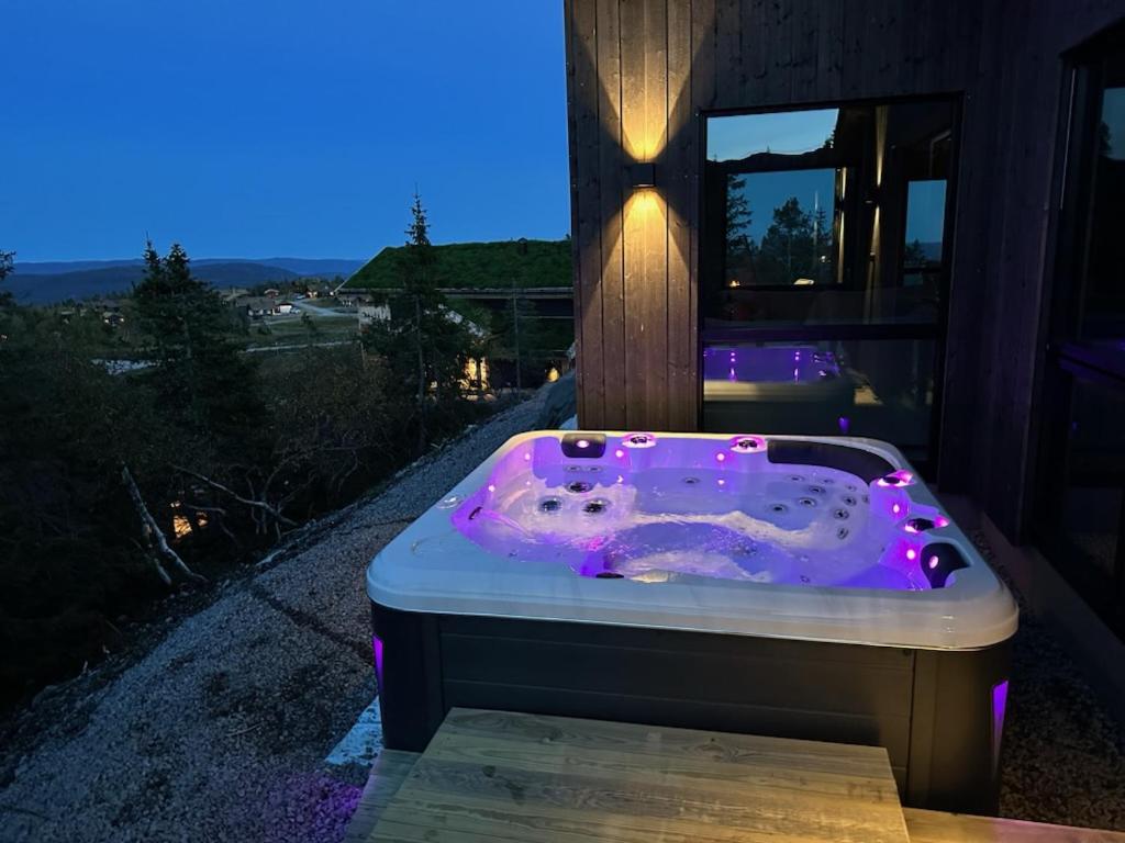 伯Stylish cabin at Lifjell with jacuzzi and sauna的房屋前方设有紫色灯的按摩浴缸