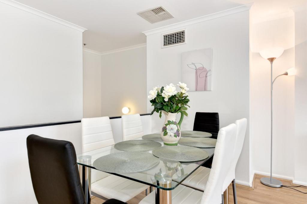 悉尼Beautiful apartment in Pyrmont的一间设有玻璃桌和白色椅子的用餐室