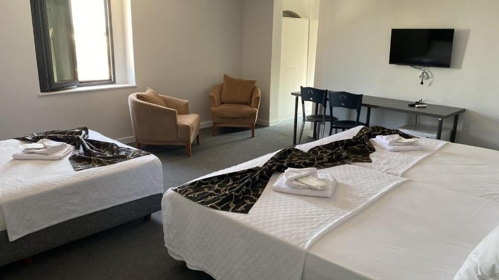 AksuRED FLAG HOTEL的酒店客房带两张床和一张桌子以及椅子。