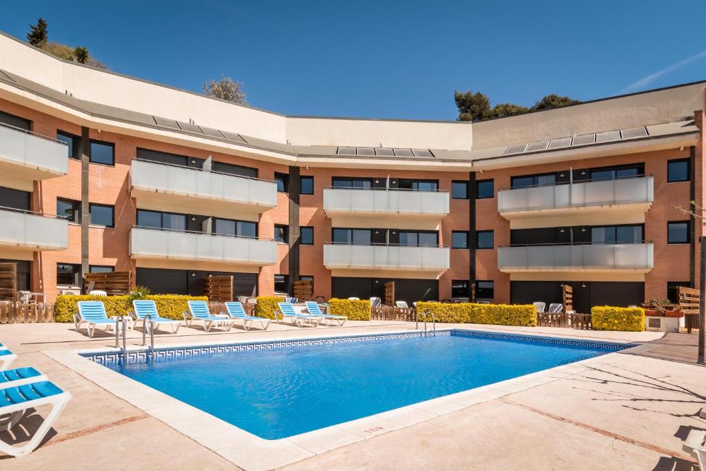 圣苏珊娜SANTA SUSANNA Chic! Apartments by ALEGRIA的享有带游泳池和椅子的建筑的外部景色