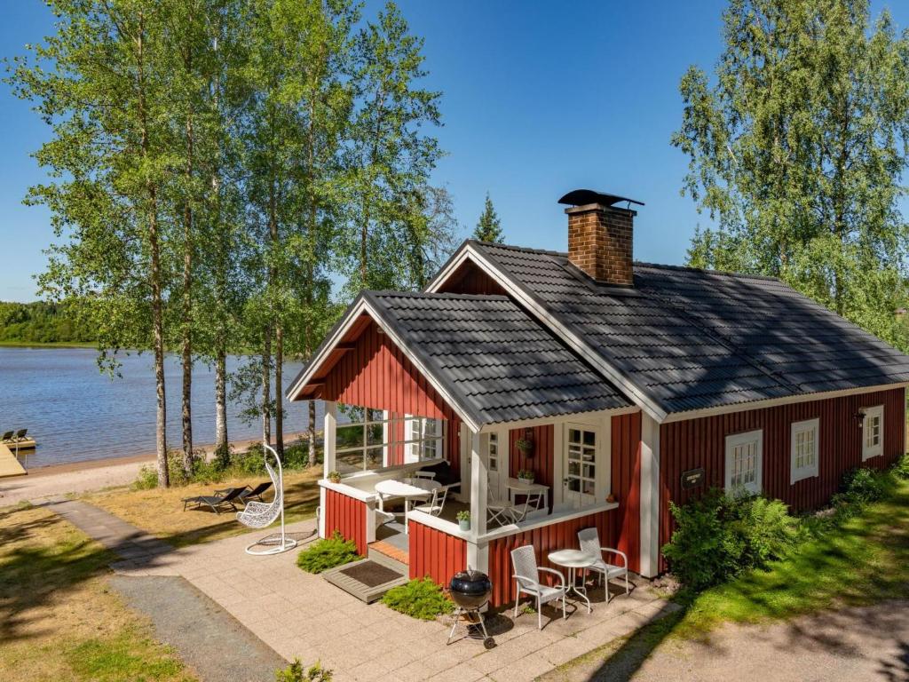 HirsjärviHoliday Home Sepelkyyhky by Interhome的水边的红色小屋,配有桌椅