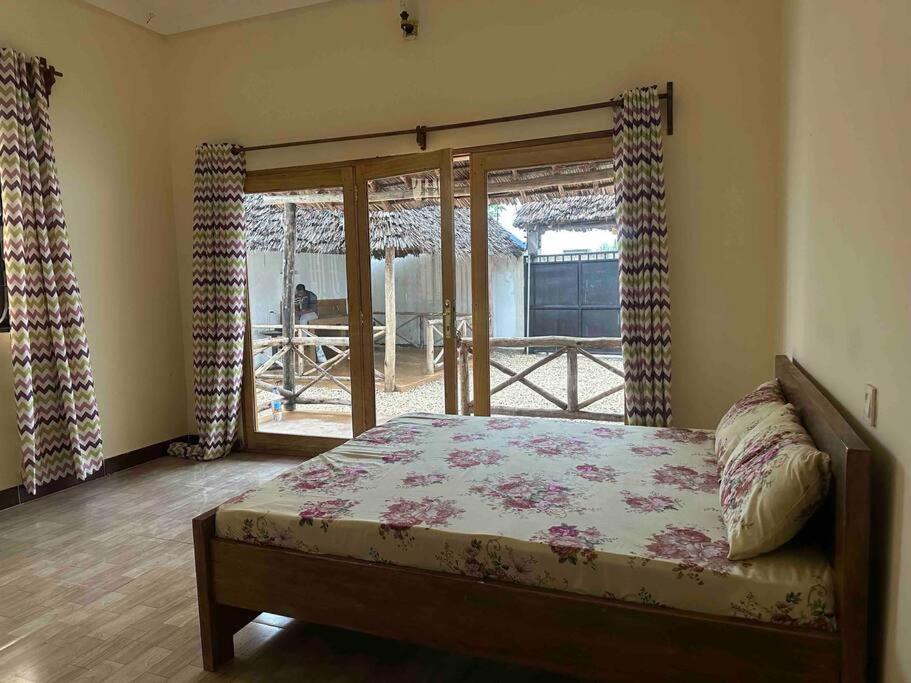吉汶瓦Bhome Zanzibar的一间卧室设有一张床和一个滑动玻璃门